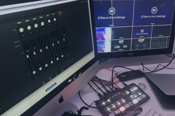 Monitor screens and sound desk at a hybrid corporate event.