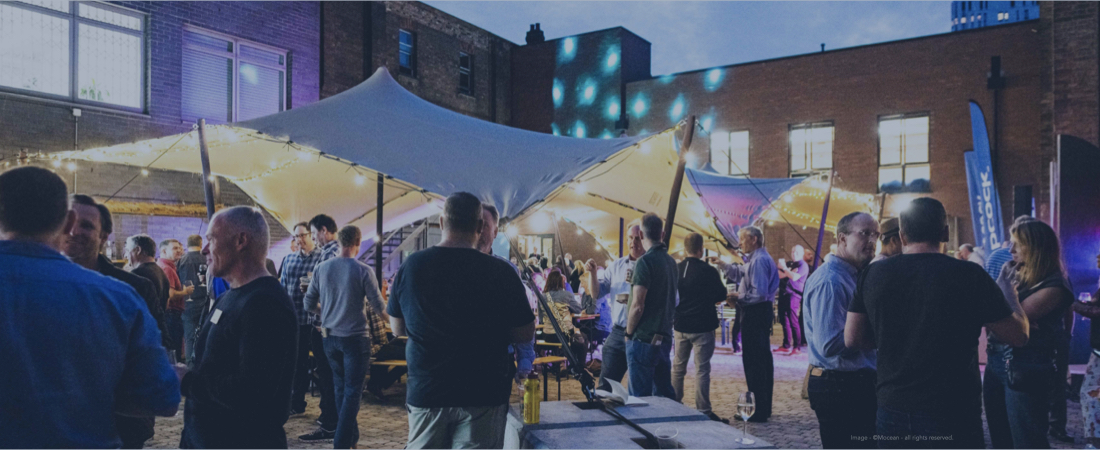 Delegates outside by a marquee networking at a corporate conference.