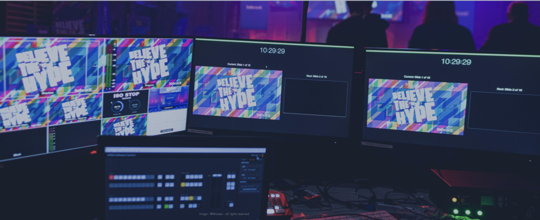 Monitor screens and sound desk at a corporate conference.