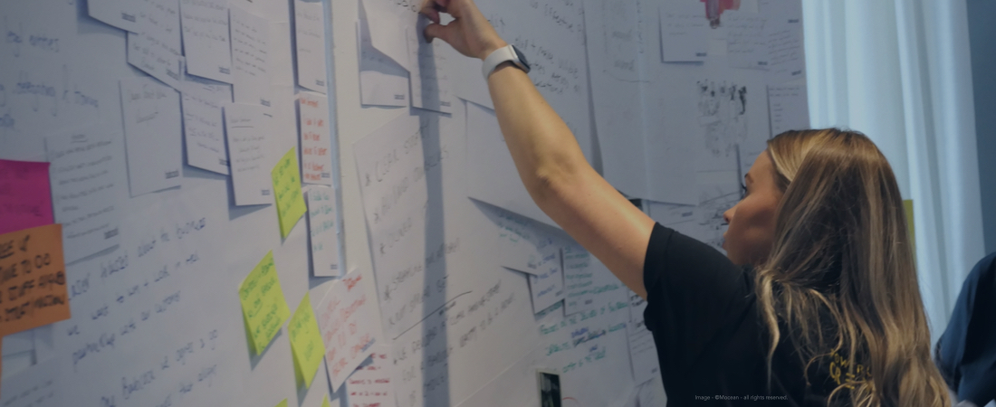 A delegate placing an idea card on Mocean’s portable ideation wall at a corporate event.
